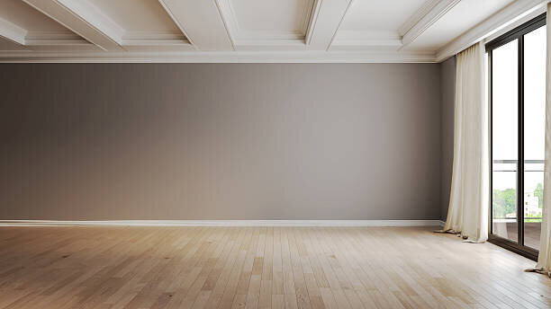 An empty living room with beige walls and a large window.